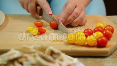 一个女人正在用一把刀在木板上切一个黄色和红色的樱桃番茄。 时光飞逝。